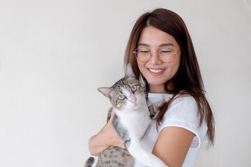 Smiling Thai woman gently hugging cat indoors