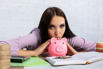 A young woman contemplates her finances while examining her piggy bank and savings strategies