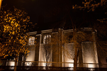 A beautifully illuminated building amidst tall trees at night, creating a serene atmosphere