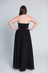 A stunning and elegant black strapless evening gown showcased beautifully from the back