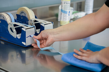 Healthcare professional's hands meticulously preparing critical medical instruments by sealing...