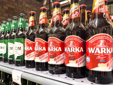 Poznan, Poland - June 7, 2025: Close-up view of multiple Warka Classic Premium Beer bottles neatly arranged on a retail shelf in a supermarket