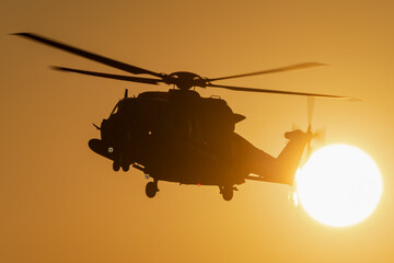 A helicopter is flying during a beautiful sunset. 