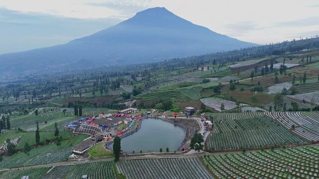 Aerial scenery of lake in the middle of plantation on the highland with mountain background. Embung Bansari with Mt.Sumbing background, Indonesia.