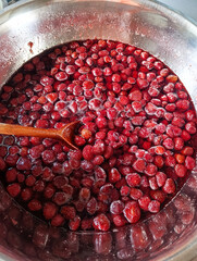Pot filled with strawberry jam and wooden spoon