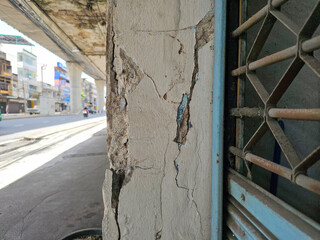 The pillars and exterior of the building are damaged and show visible cracks.