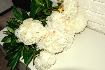 A floral bouquet of white peonies against a brick wall is a tranquility and aesthetics of the house.