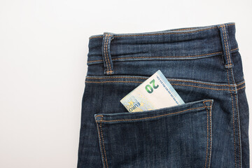 Denim jeans with a twenty euro banknote partially visible in the back pocket, showcasing casual...