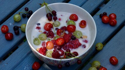 Ein Müsli mit Früchten aus dem Garten auf grauem Holz.