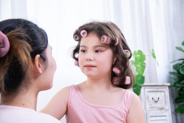 Kids, cosmetic, child, beauty, girl, happy girl with curlers smiles while interacting with Asian...