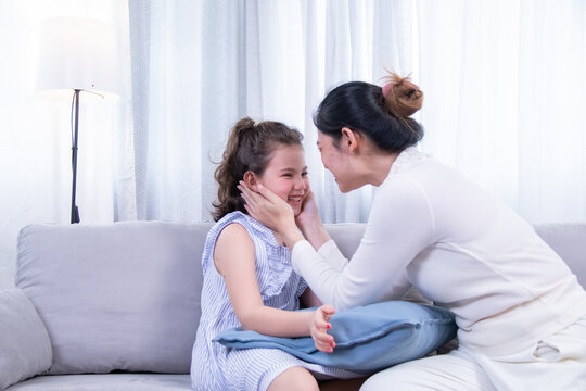 Kids, mother, bonding, beauty, love – Asian mother hugs her biracial daughter while admiring her painted nails, capturing warmth, family closeness, and joy from a shared beauty experience at home