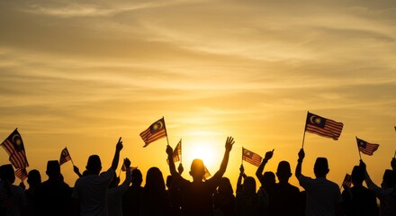 silhouette of people holding Malaysian flag in the air at sunrise