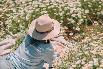 Daisy Hat Woman: Relaxing in field, daytime picnic, enjoying nature. Carefree summer mood.