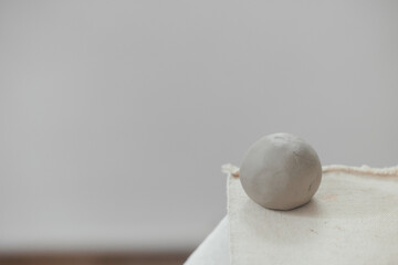 Round clay ball for pottery and sculpting on a blurred background. Raw ceramic material