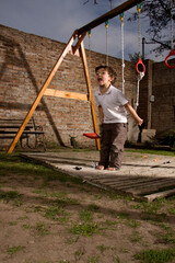 Young Boy Playing Enthusiastically on Wooden Swing Set in Backyard
