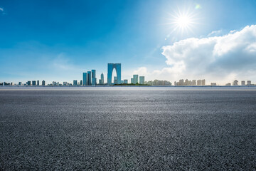 Empty asphalt road and city skyline with modern commercial buildings in Suzhou, China.