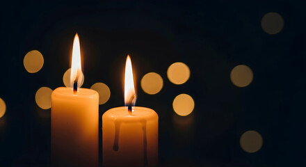 Two burning candles in dark background