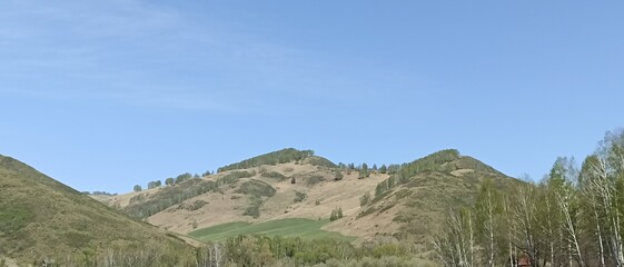 A tranquil landscape showcasing rolling hills and vibrant greenery beneath a bright blue sky. This beautiful nature scene is perfect for travel, tourism, and outdoor themes.