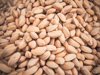 Close-up image of a large pile of pistachios with a warm, natural tone. Heap of pistachios