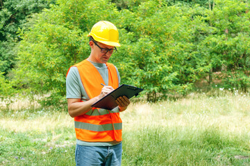 Engineer ecologist man in the forest marks of the ecological situation. Eco technic with clipboard...