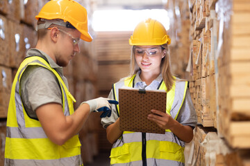 Male and female warehouse workers working laptop computer at wooden warehouse storage. Team of...