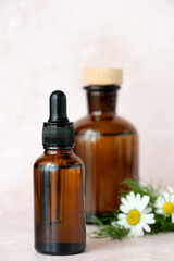 Natural aesthetic ideal for herbal remedies. Brown glass bottles arranged artfully alongside a of chamomile flowers. Alternative medicine, healthy and well-being concept