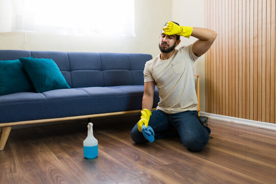 Frustrated housekeeper kneeling on floor taking a break from cleaning house
