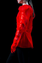 Cropped female figure dressed in a chic red fancy blouse and gloves walking on black background.
