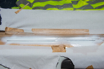 In a workshop, technician prepares for car window tinting by taping and masking the edges for a...
