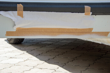 Taped area on the undercarriage of a vehicle indicates ongoing repair work, ensuring a clean...