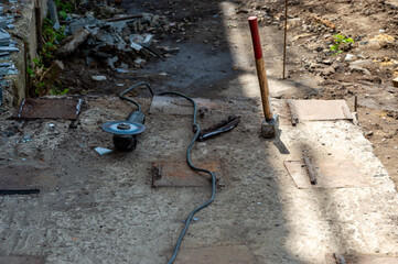 Construction tools are scattered on the ground, including a grinder, hammer, and debris, revealing...