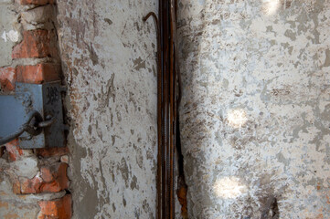 Metal rods display rust and wear as they extend from an aged wall in an industrial location,...