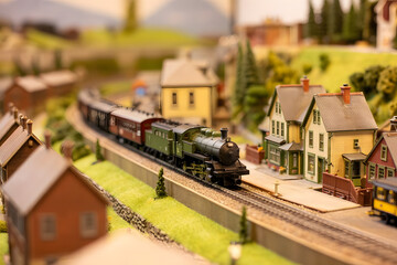 Photo of detailed miniature railroad diorama featuring steam train, quaint town, rolling green hills, tilt-shift blur effect, and warm sunlight enhancing depth.