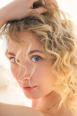 Close up portrait of an attractive stunning blonde woman with wide clear blue eyes. Backlight.