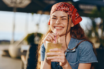 smiling woman in modern boho-western denim street style drinking beverage outdoors, film color,...