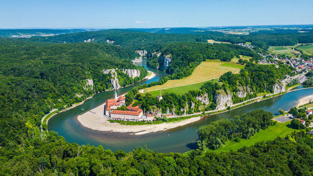 Kloster Weltenburg on the Danube River, Germany, shot from a drone in summer. Historic Benedictine monastery surrounded by forested cliffs and dramatic river curves near Kelheim