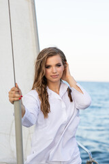 Beautiful young girl in a white shirt at sea on a yacht in summer