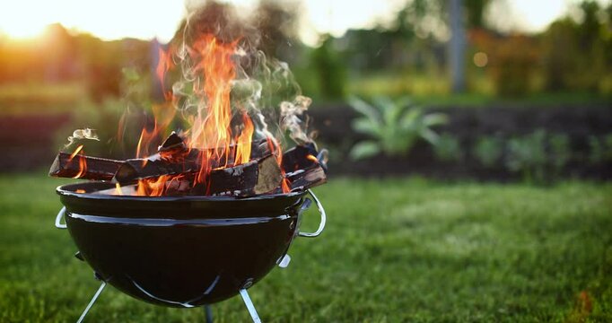 BBQ grill with fire outdoors. Evening time before sunset. Slow motion movement to the right