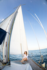 Beautiful young girl in a white shirt at sea on a yacht in summer