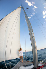 Beautiful young girl in a white shirt at sea on a yacht in summer