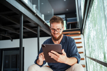 A Young Professional Engages with a Tablet in a Cozy, Contemporary Home, Highlighting Comfort