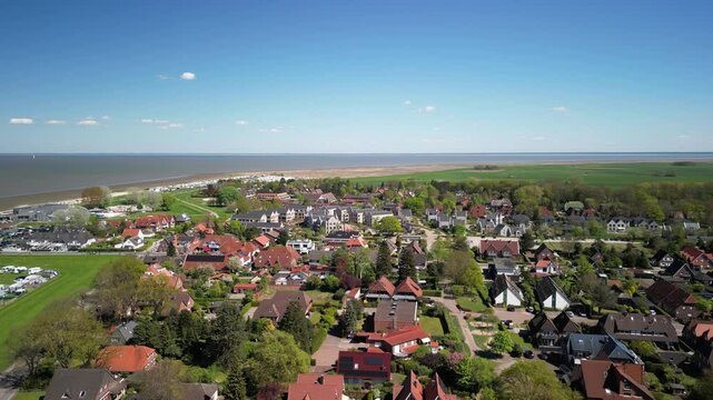 Dangast. Aerial view of coastal town showcasing residential homes, green landscapes, and serene beach, highlighting the beauty of nature and community living