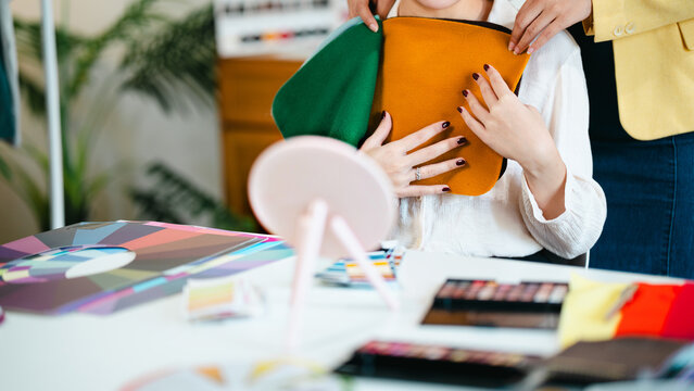 Color specialists consulting female customer with personal palette guide and fabric samples at beauty studio