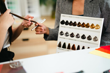 Color specialists consulting female customer with personal palette guide and fabric samples at...