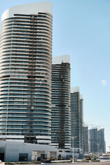 High-rise buildings with glass facades rise along a wide city street in a modern business district