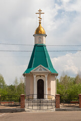 A quaint orthodox chapel with a gleaming golden dome against a partly cloudy sky. Victory Park in...