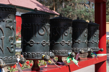 A row of traditional Buddhist prayer wheels, representing faith and spirituality. Datsan in Chita,...