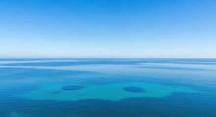 Obraz premium The vast expanse of the tranquil ocean merges with a bright blue sky.