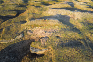 Drone view of ancient hills resembling the head of a dragon or a mythical beast. A mysterious landscape in the rays of the setting sun.