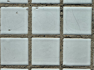 Close-up of weathered white tiles and concrete, with a detailed texture.